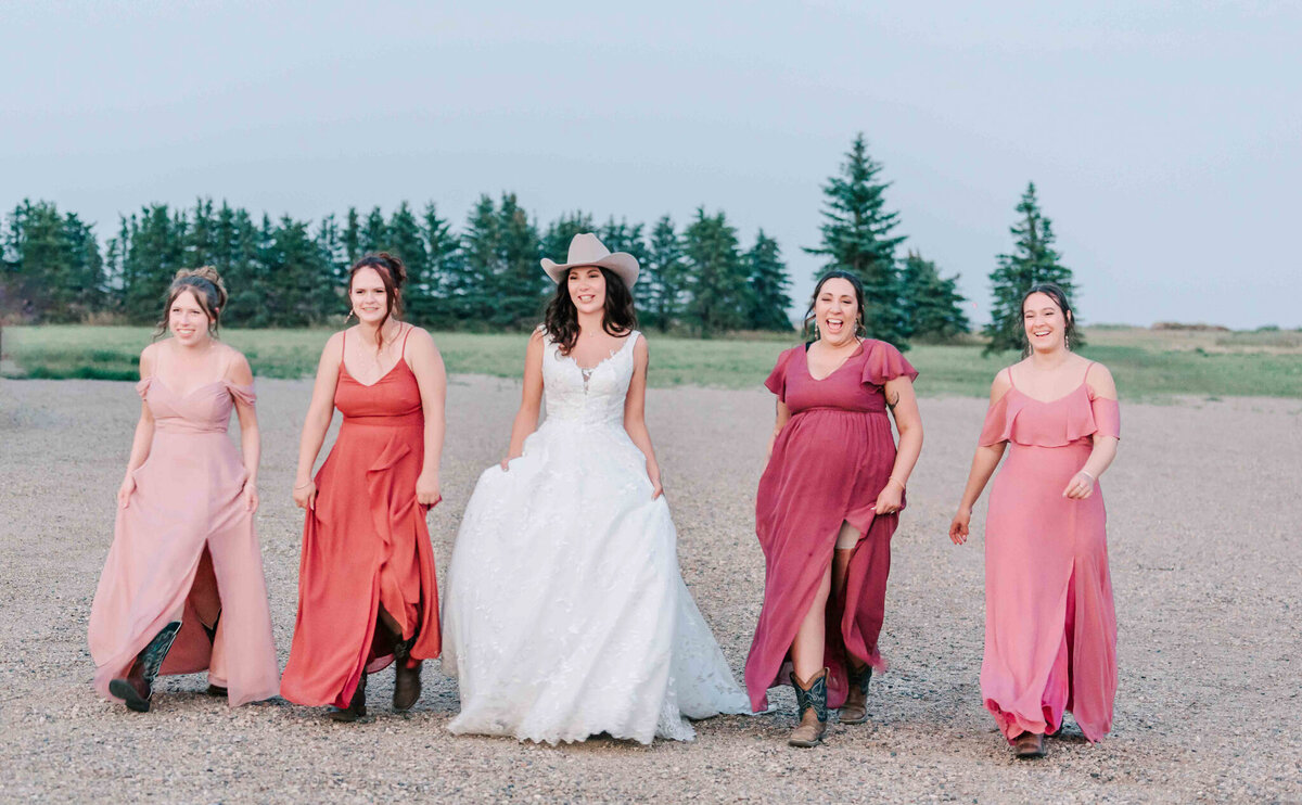Bride walks on gravel with her bridesmaids. 