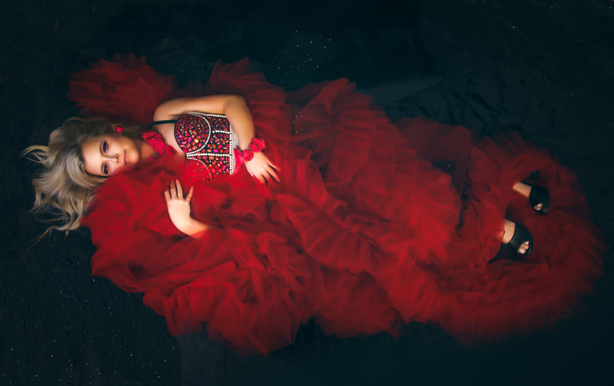 savannah-boudoir-and-glamour-gorgeous-woman-laying-down-in-red-fluffy-robe-with-flowers-applied-as-jewelry