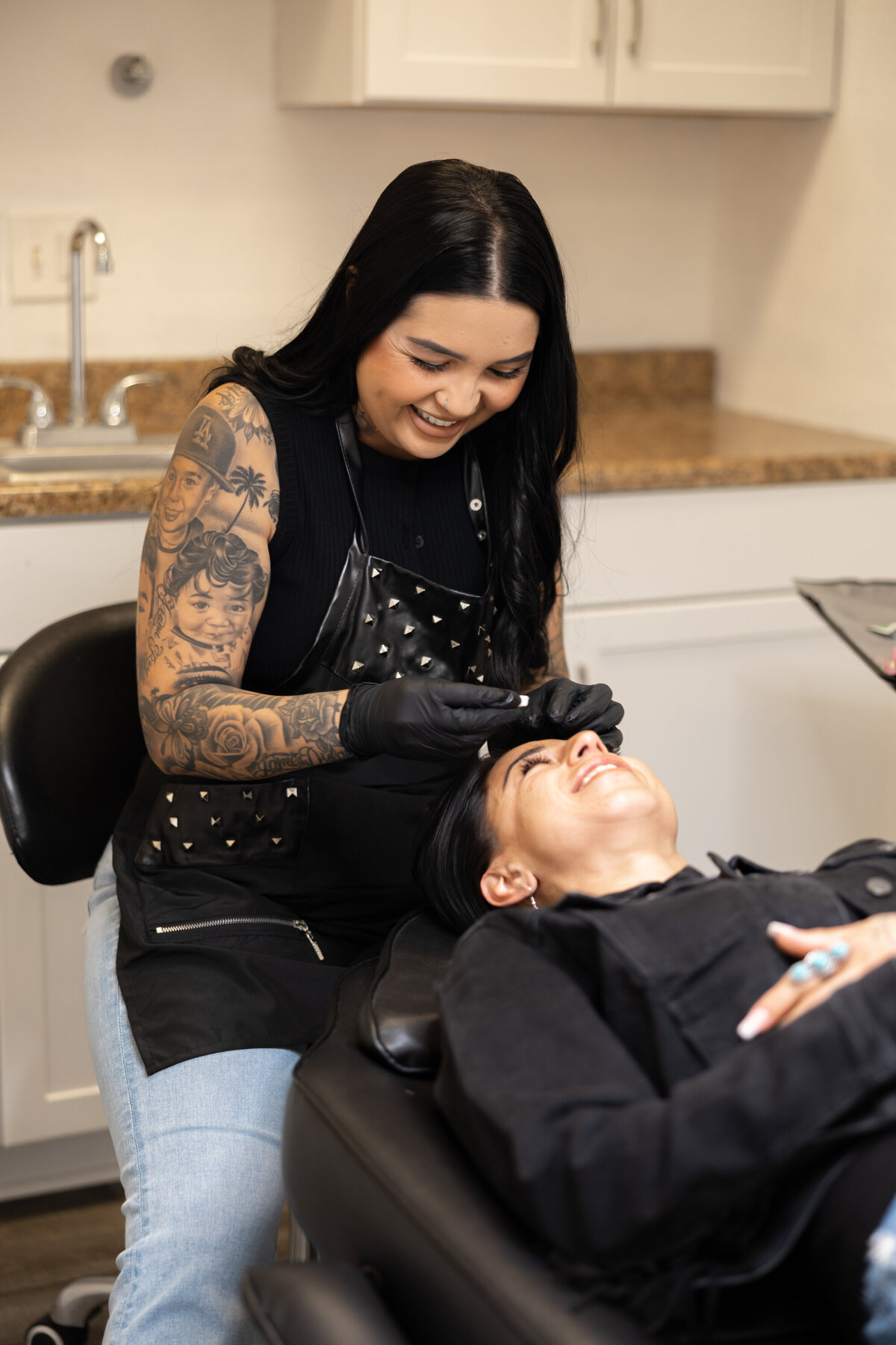 Branding photo of tattooed woman with long dark hair smiling in modern studio. Photograph by Yucaipa branding photographer Kaitlyn Dawn Photography.