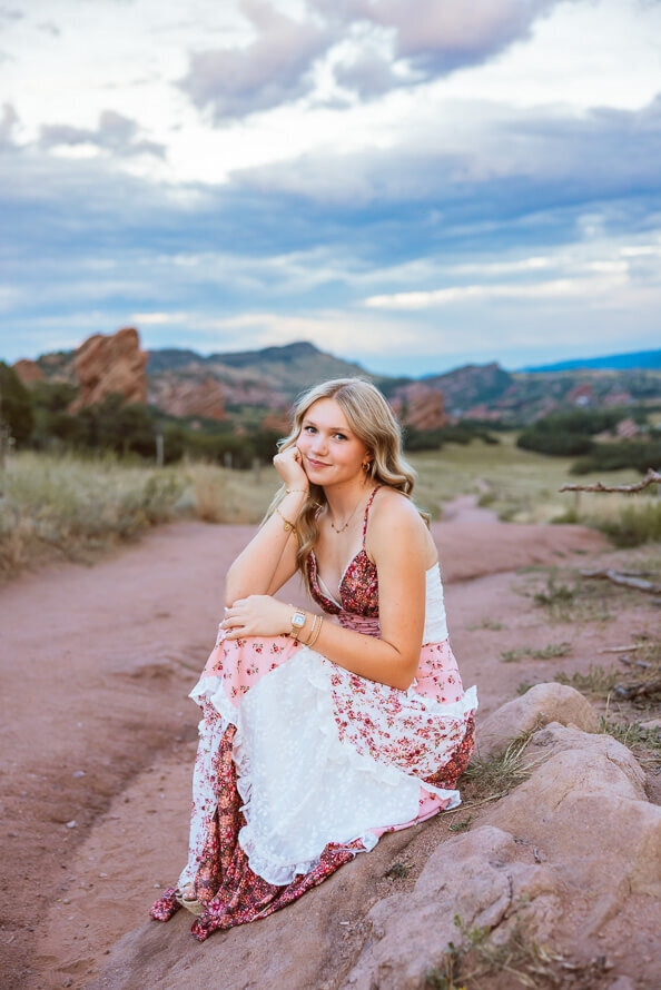 Girl pulls knees up and smiles at camera for senior photos.