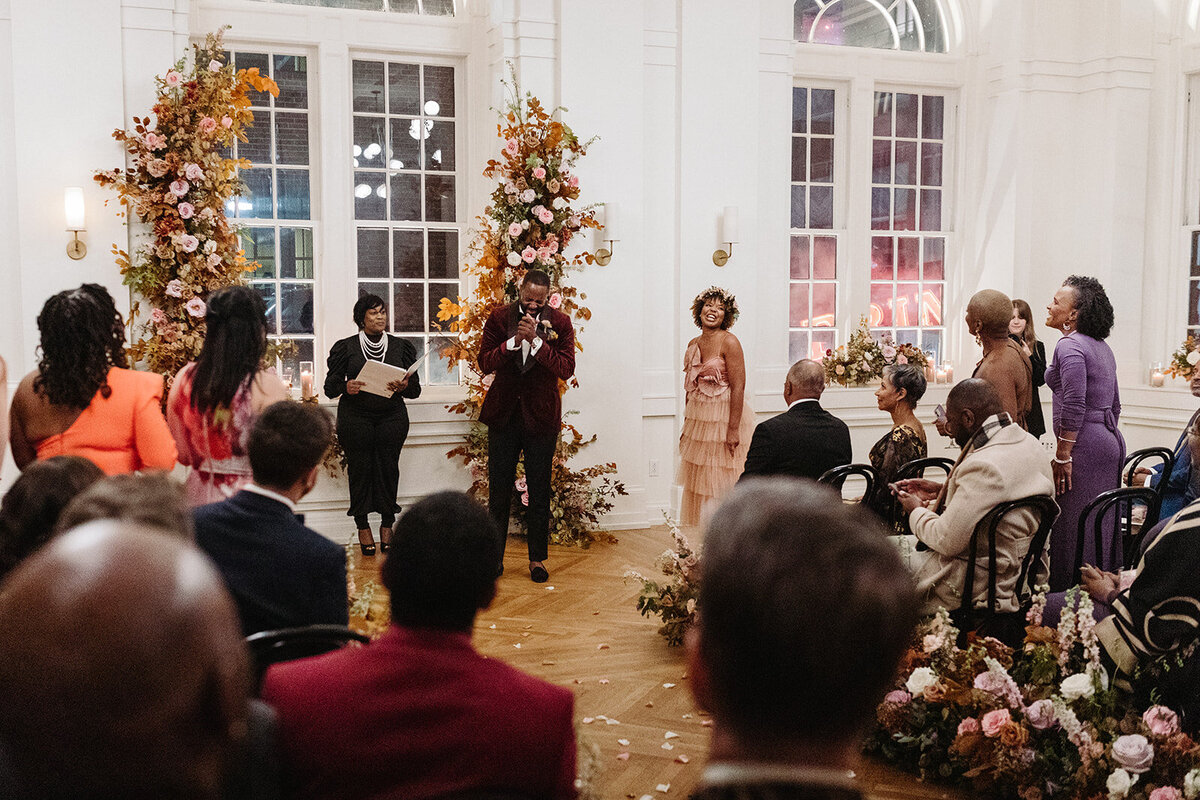 Artful asymmetrical floral wedding ceremony backdrop sets the autumnal hues of mauve, dusty rose, burgundy, terra cotta, and copper florals composed of roses, copper beech, delphinium, raintree pods, mums, and fall foliage. Design by Rosemary and Finch in Nashville, TN.