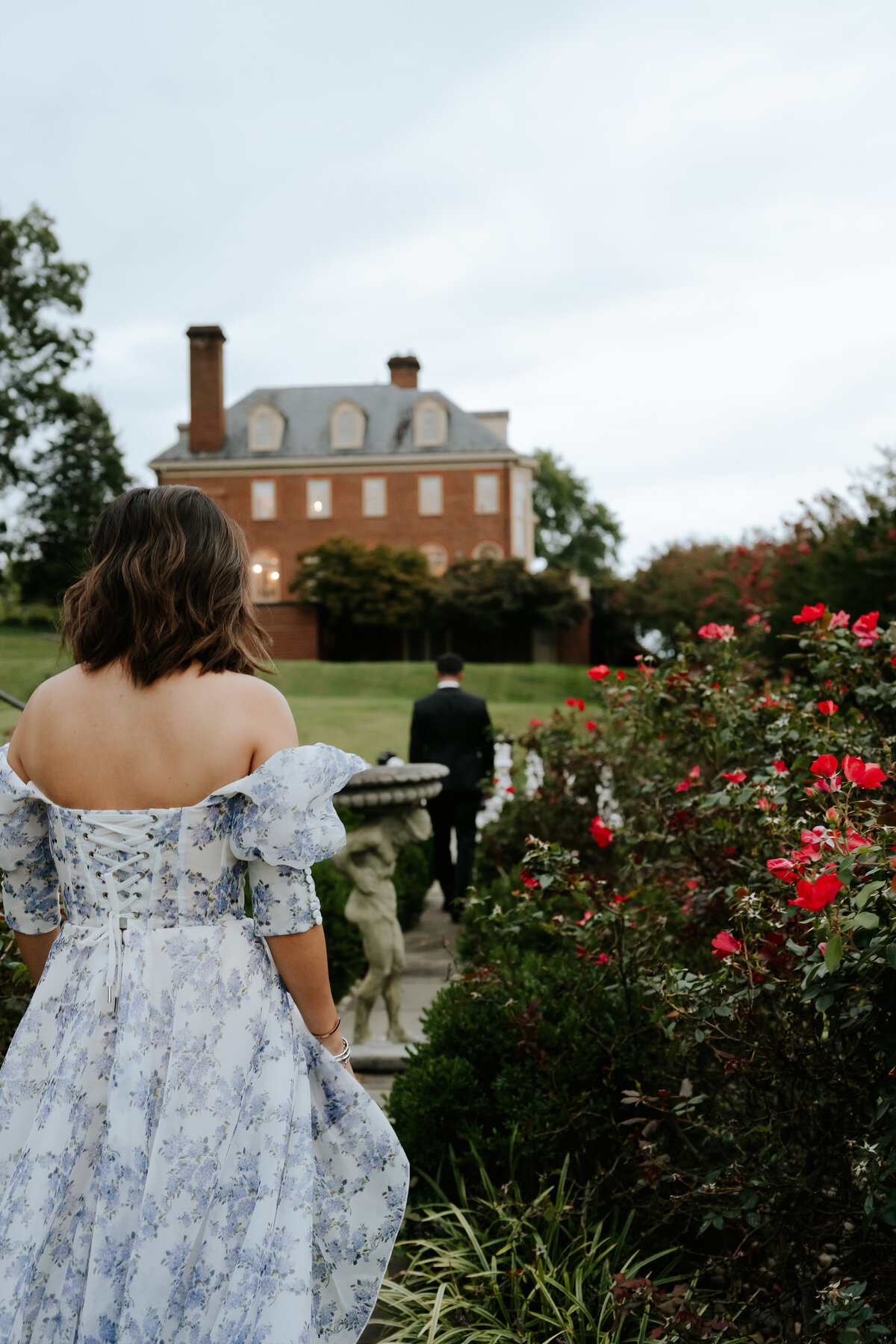 woman looking at partner from behind rose bush at estate