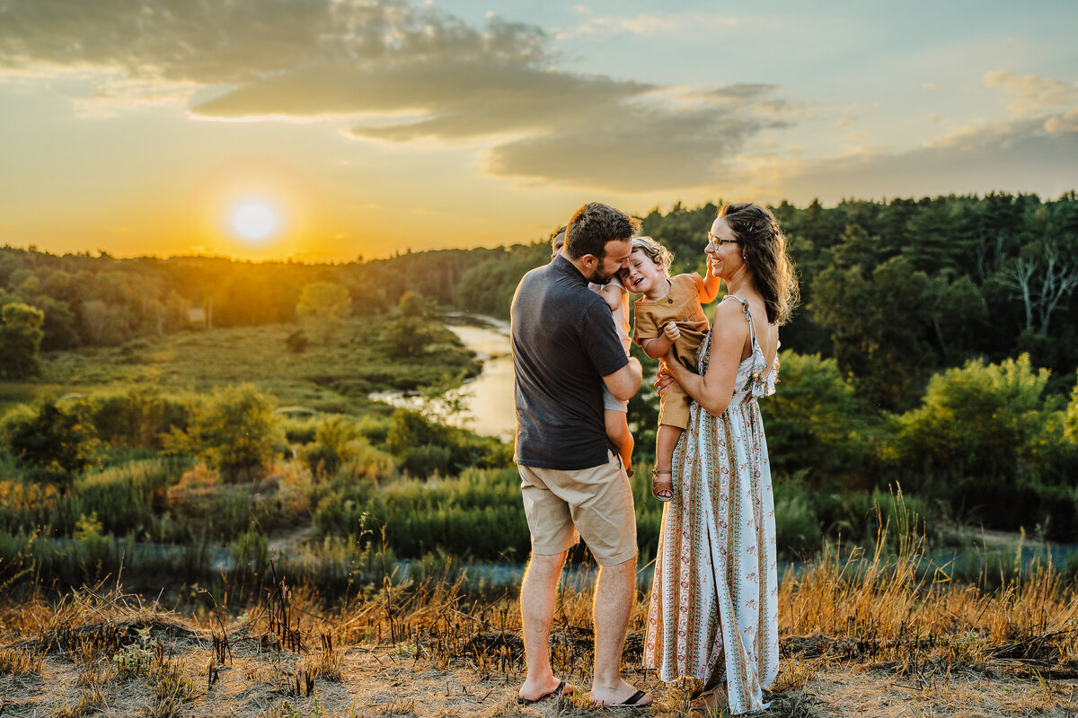 family stands at sunset at an overlook