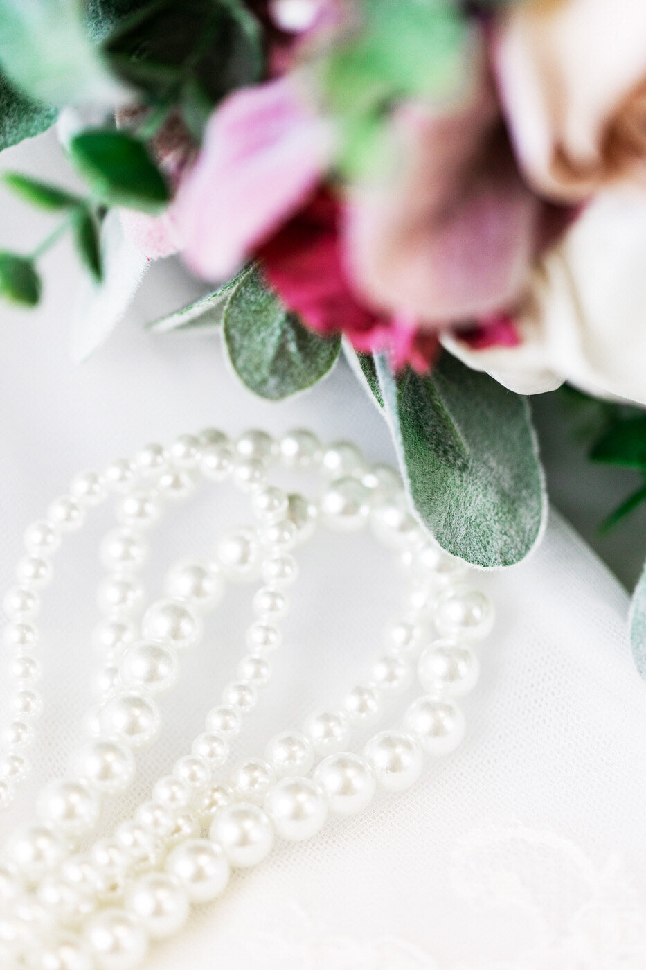 Bridal Pearls Next to Bouquet of Flowers