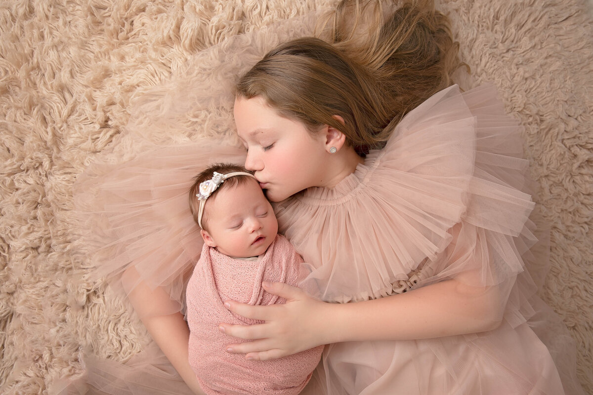 A joyful portrait of siblings welcoming their newborn brother or sister. Perfectly captured moments from our Phoenix-based newborn photography sessions.