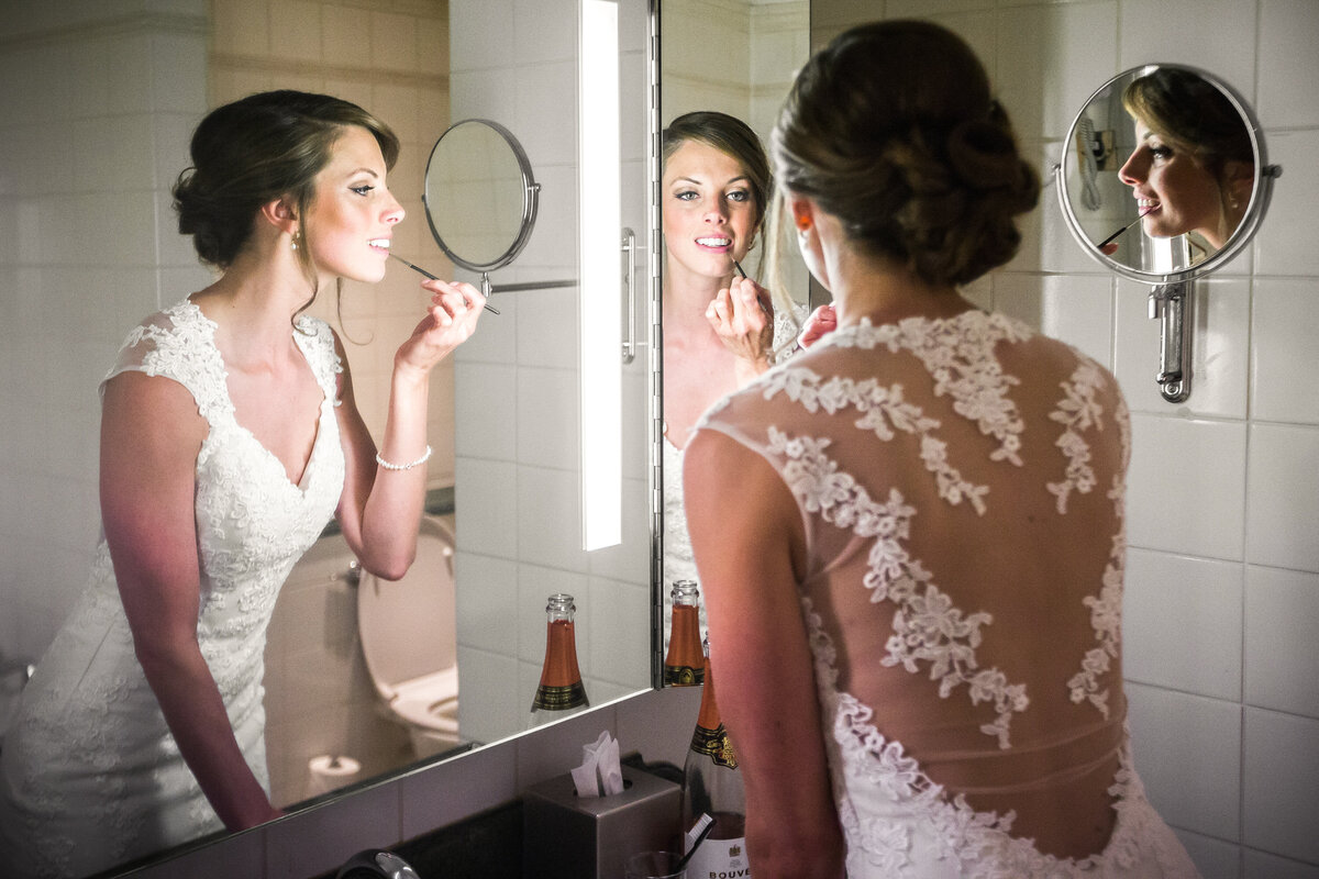 Bride putting on lipstick before ceremony in mirror