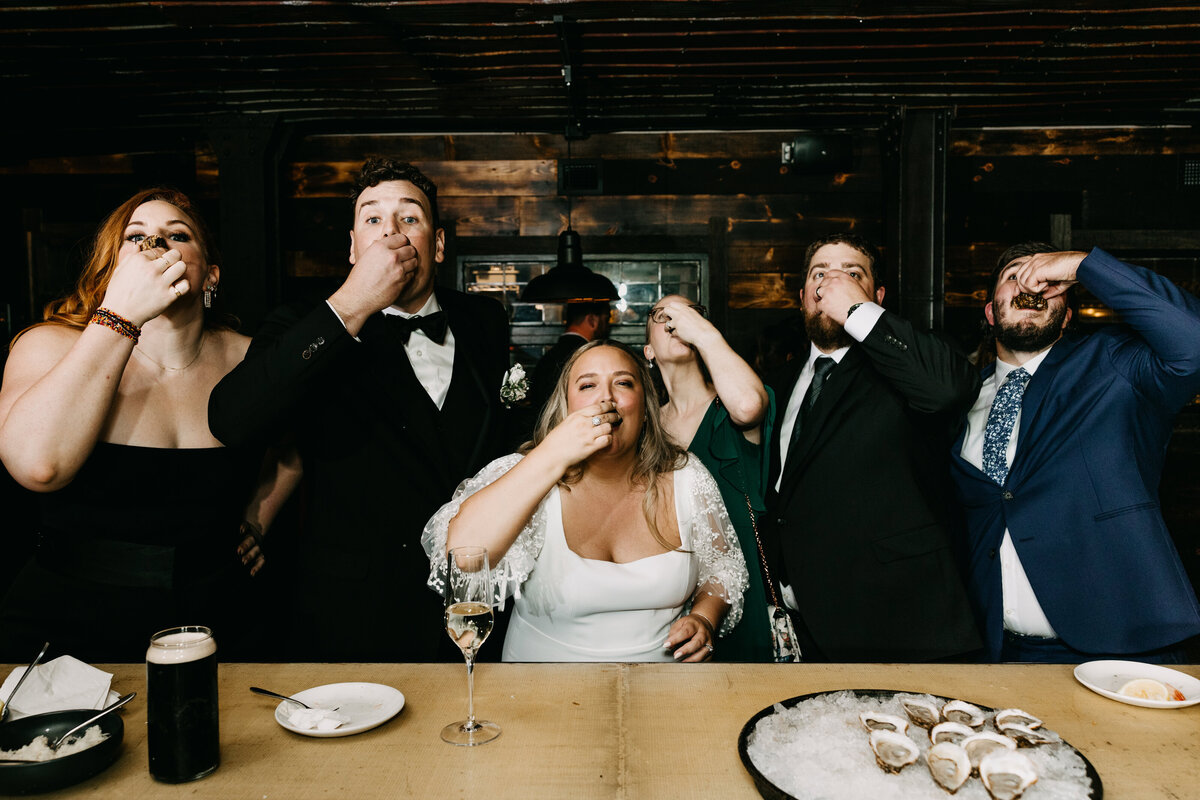 Bride, groom, bridesmaids, and groomsmen in similar poses as they eat together