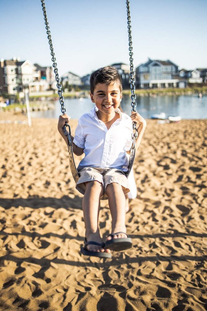 A little boy in a white collared  shirt is swinging