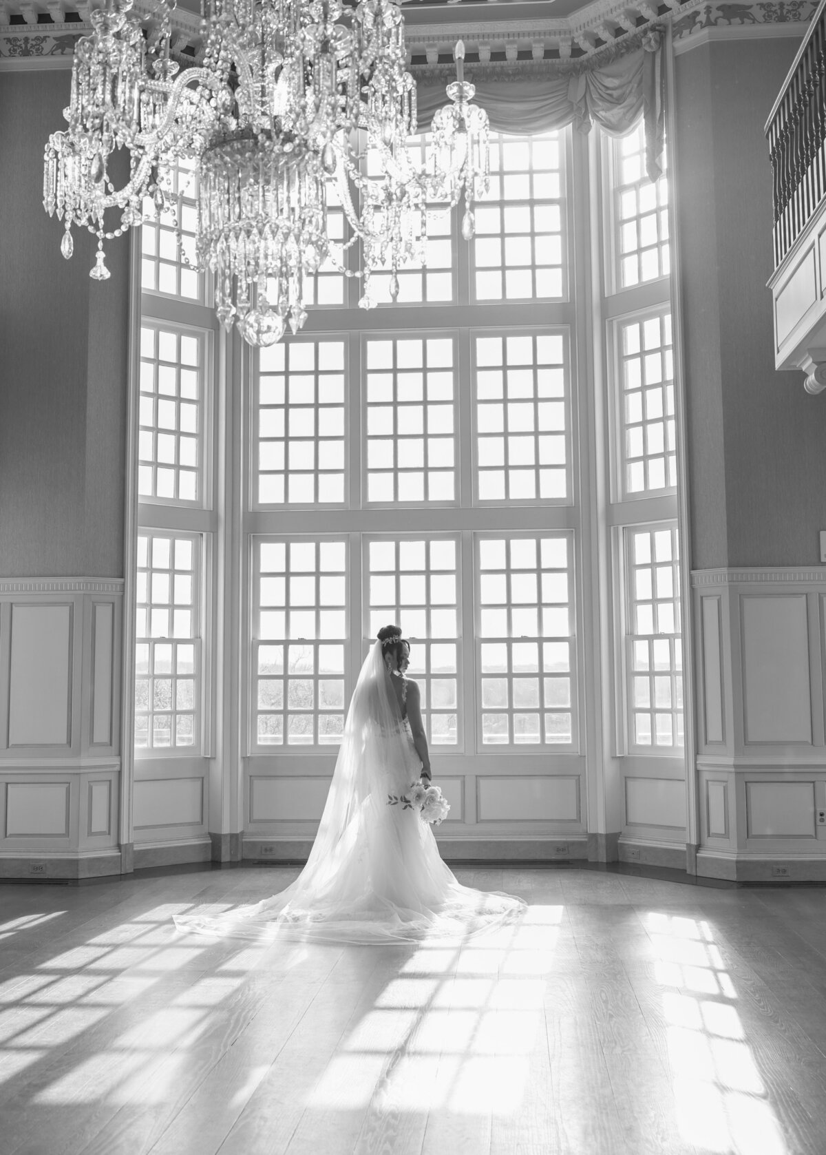 bride with white dress holding bouquet with mansion elegant windows