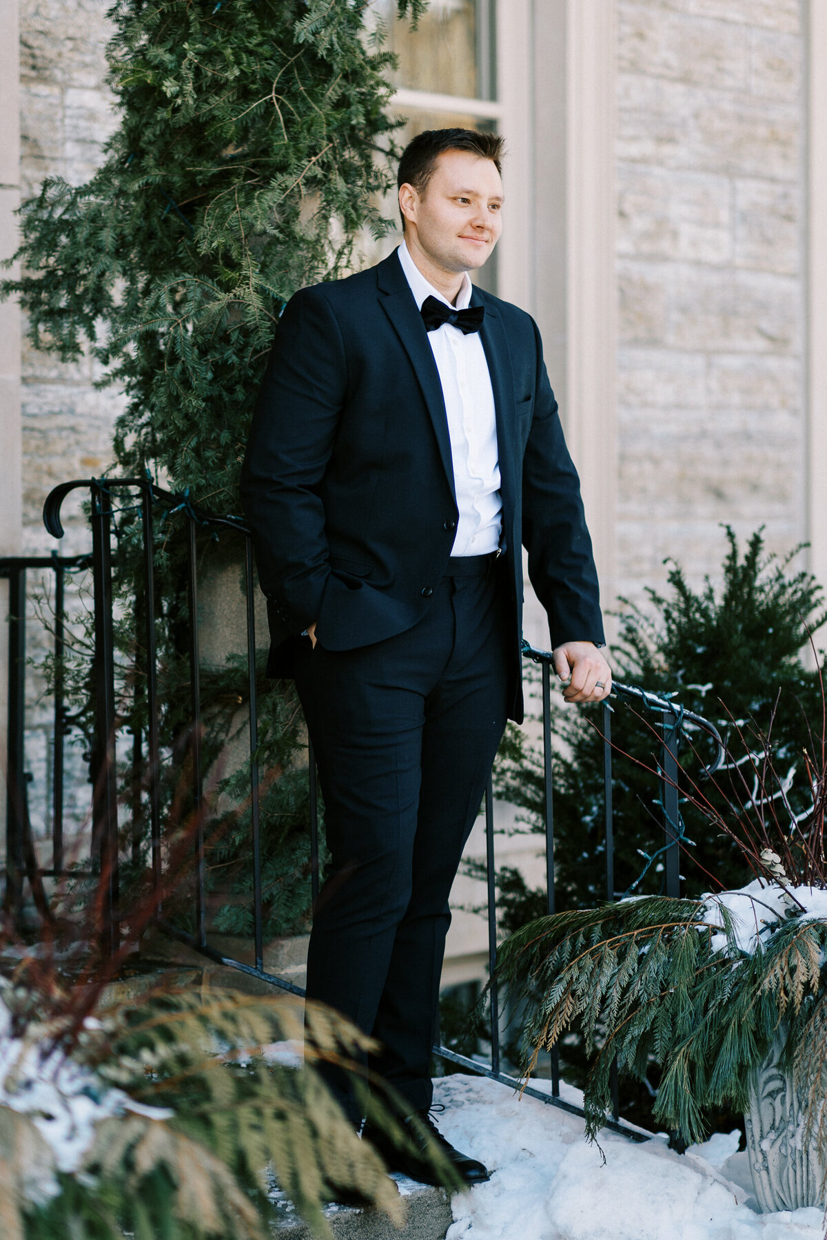 Groom posing away at the entrance of the building in a black suit on his wedding day.