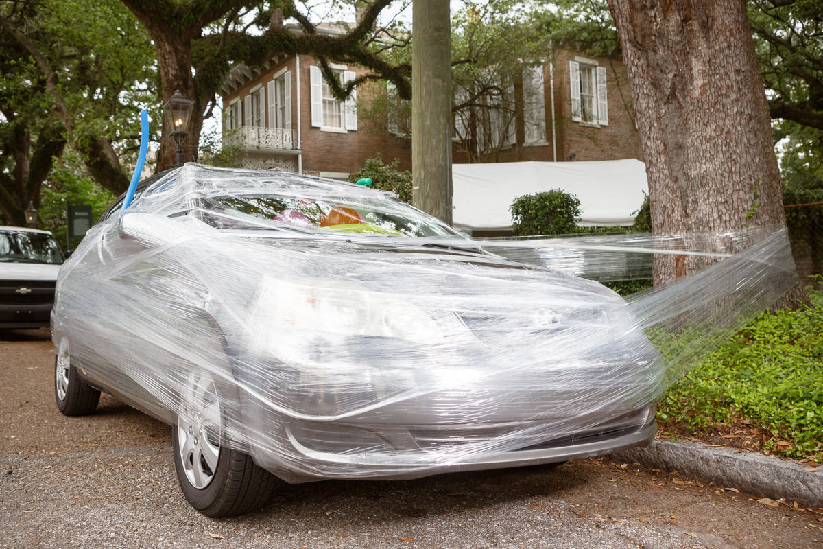 The couples car for leaving the wedding reception is attached with plastic to a tree and filled with balloons.