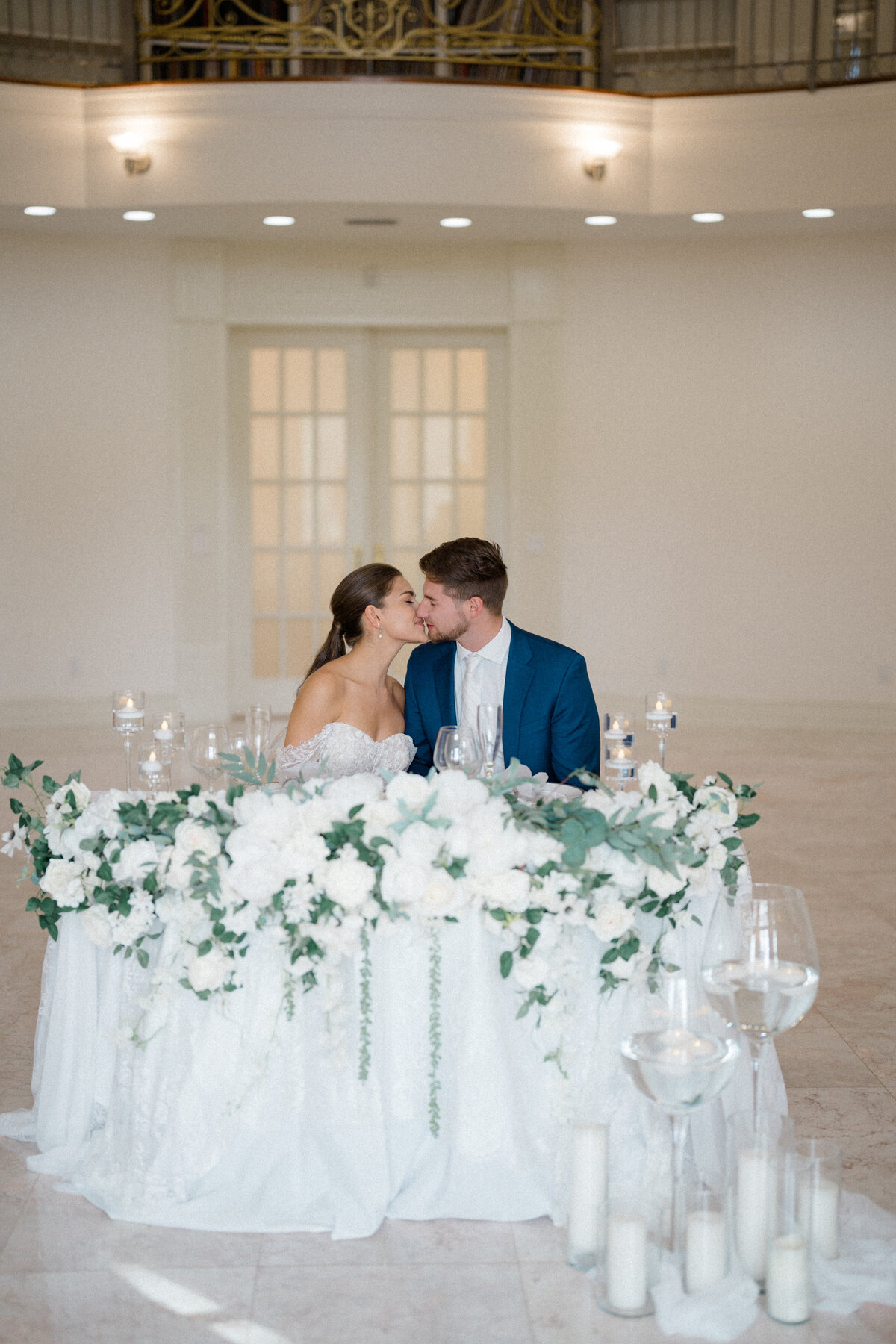 Bride and groom seated at an elegantly decorated sweetheart table with floral arrangements and candlelight, designed by In Full Bloom Event Planning & Design