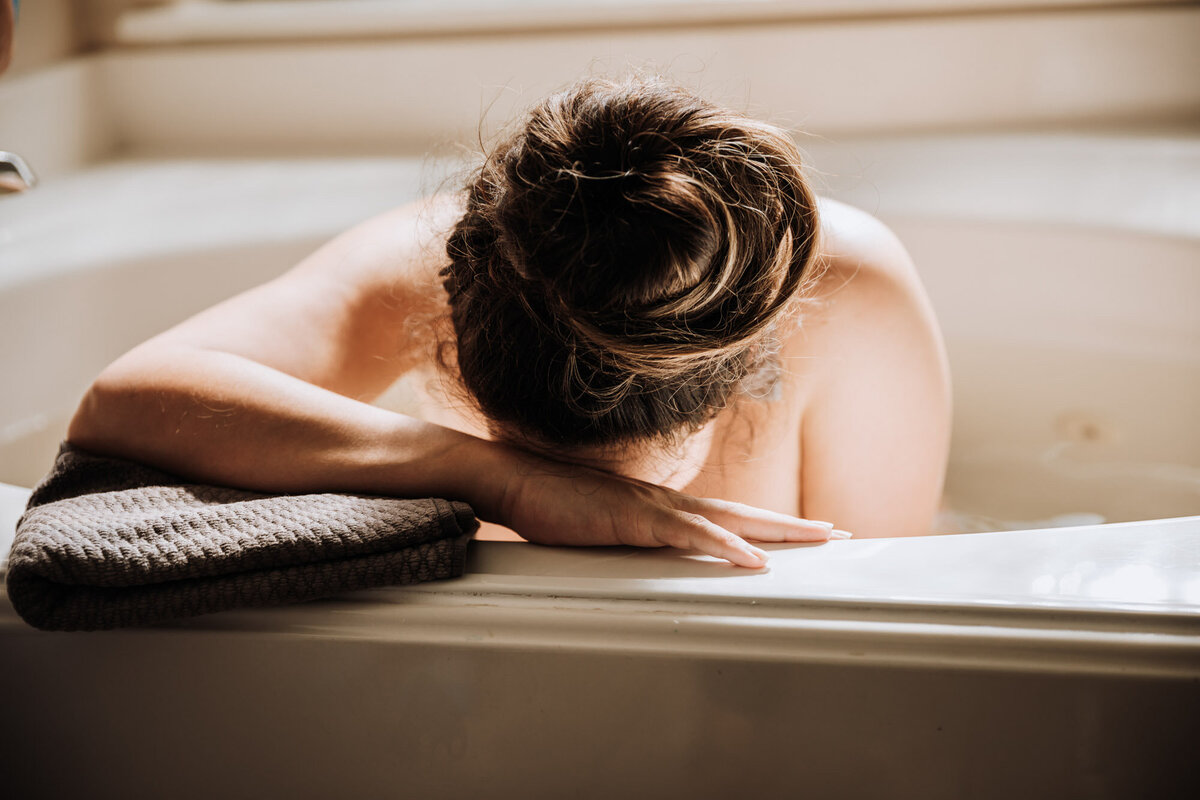 woman with forehead on edge of bath tub