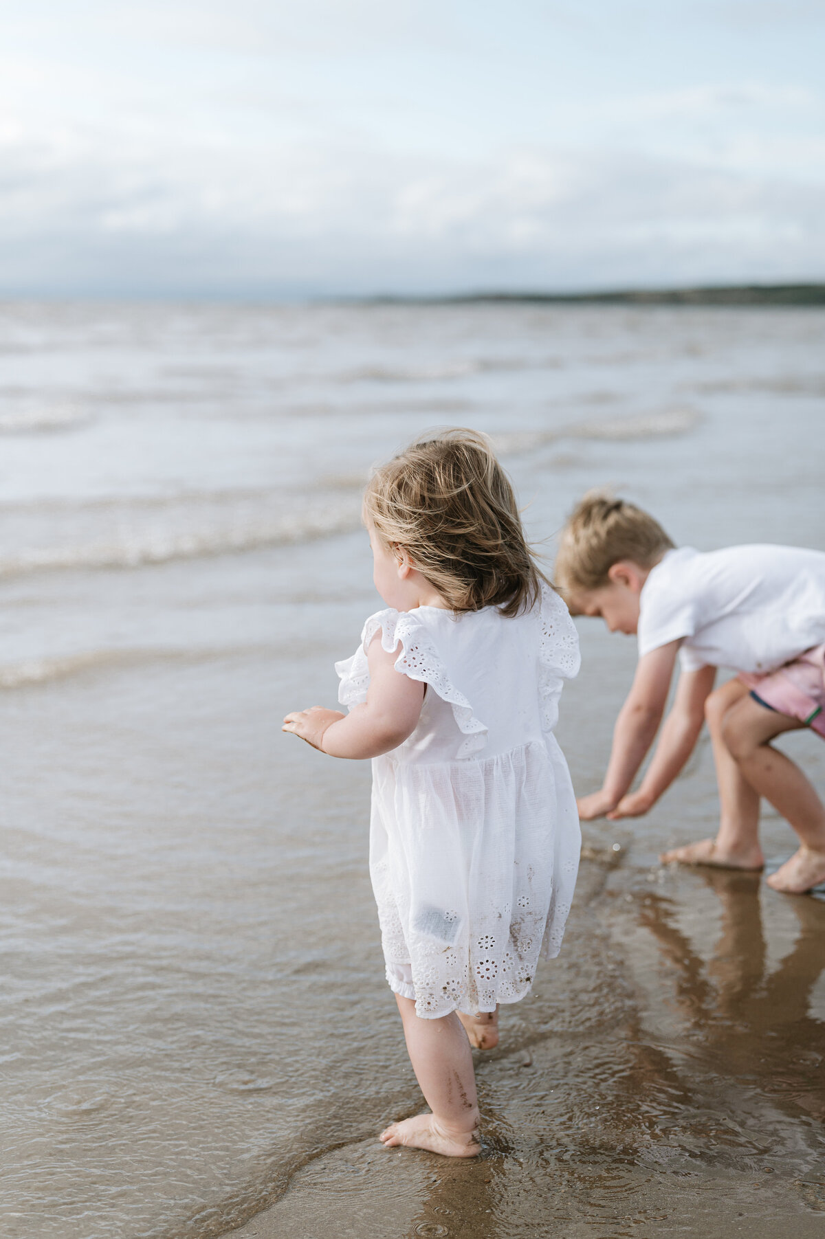 Family photography of two children playing in the sea on a beach near Bristol