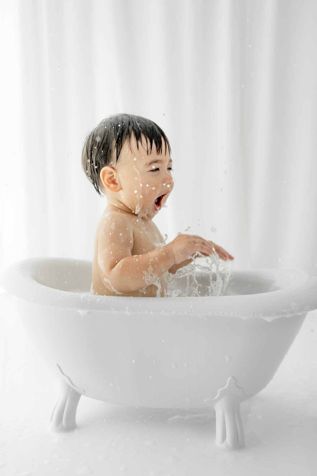 Boy in bubble bath during themed cake smash session— captured by Alliston and Barrie cake smash photographer.