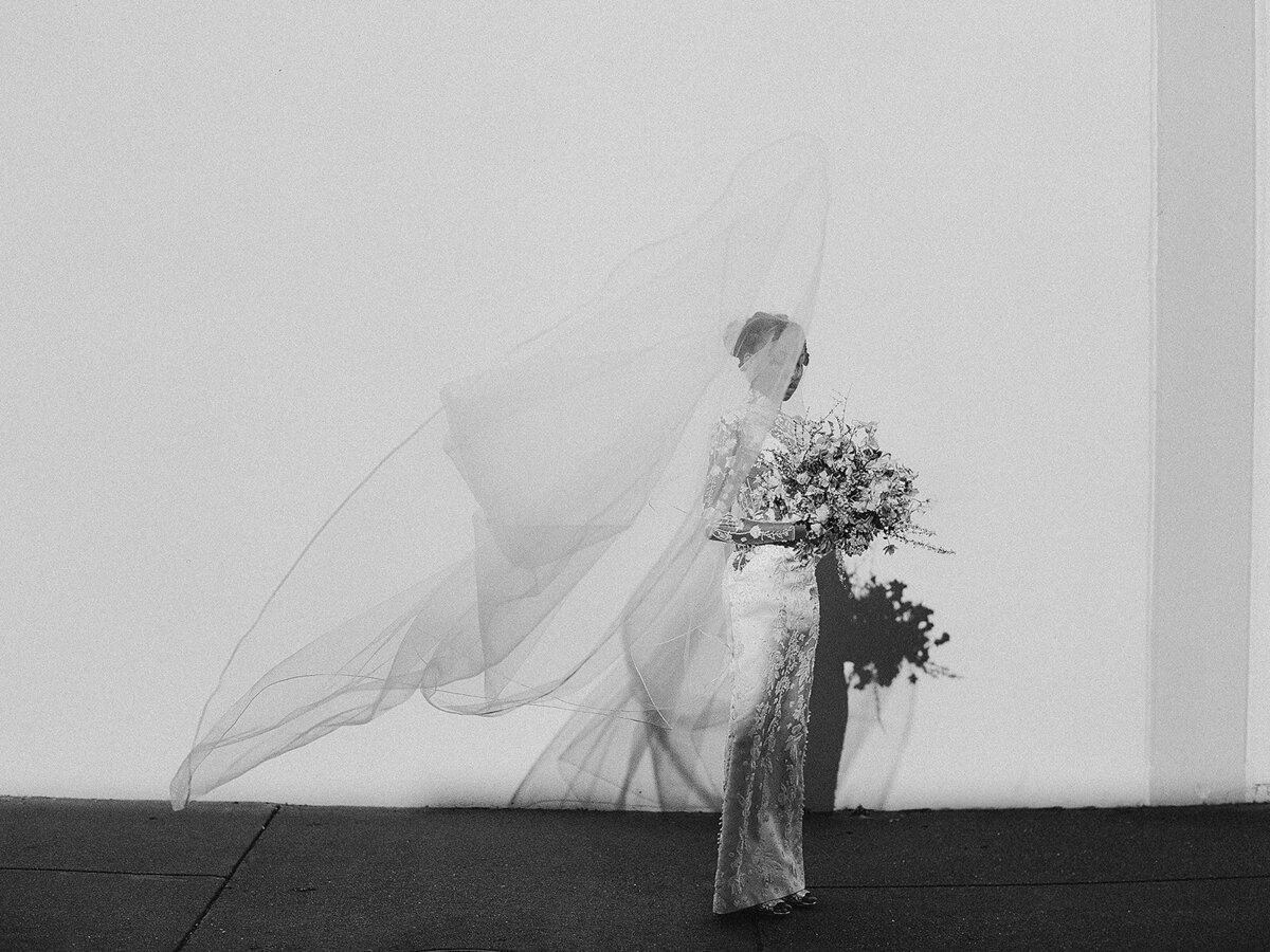 Stunning black and white of a bride with her veil blowing in the wind. Photo was taken on black and white film  