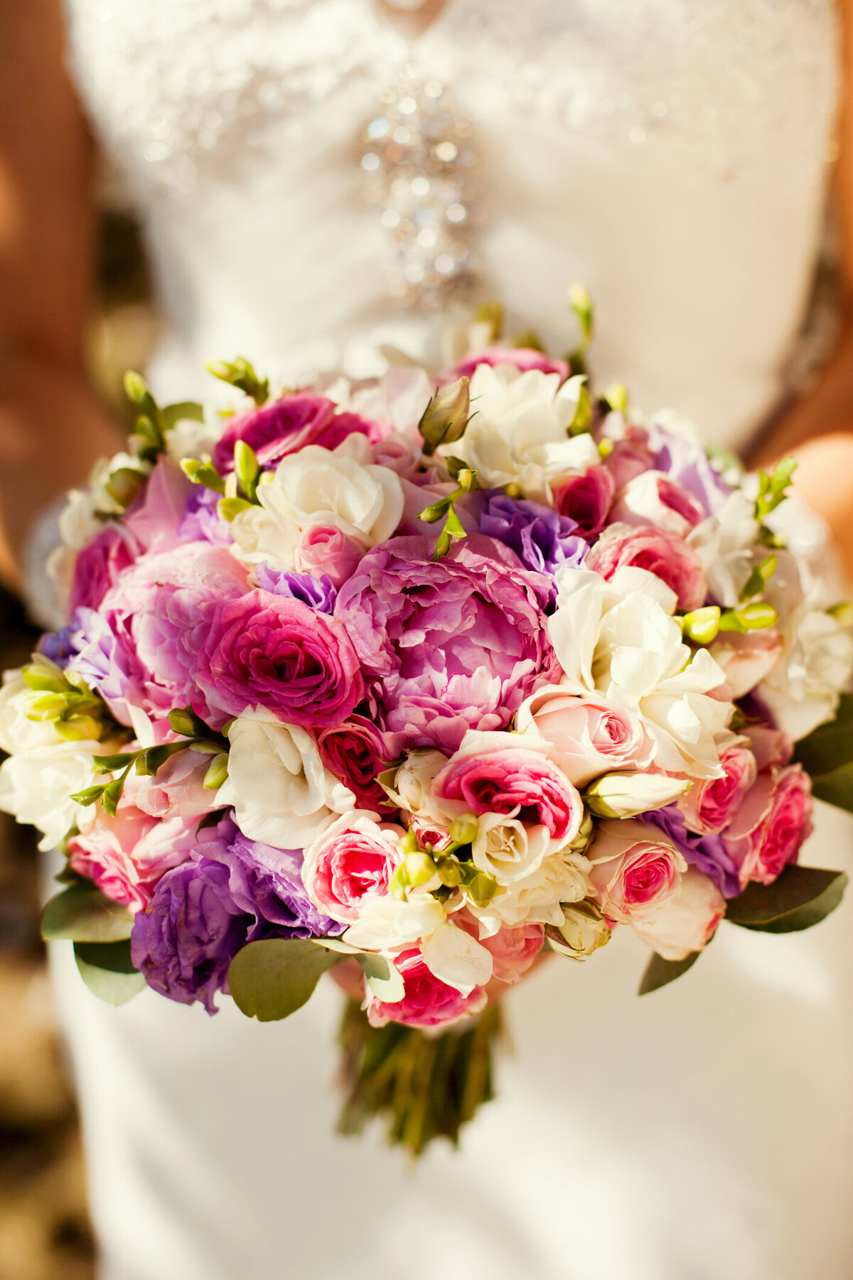 Bride holding a vibrant, colorful bouquet featuring lush florals, adding a bold and romantic touch to her wedding day look by In full bloom Event planning and design