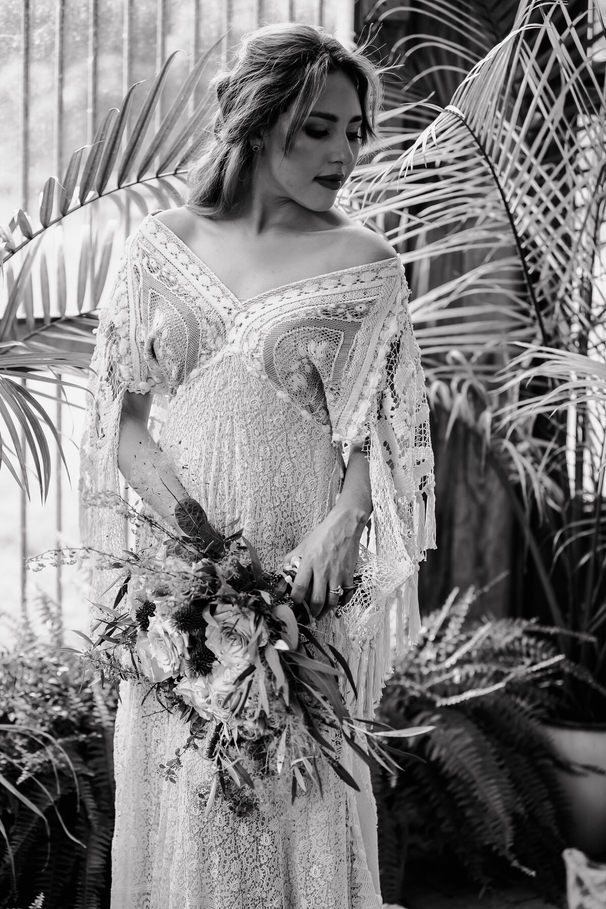 bride holding bouquet in greenhouse in black and white