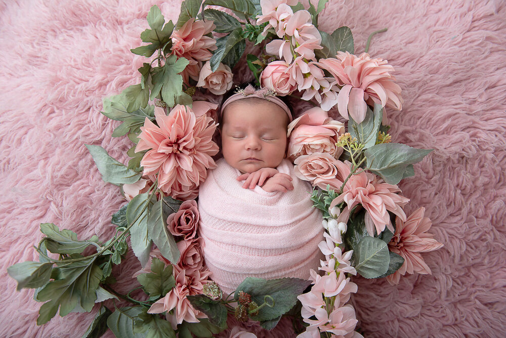 Baby girl wrapped in pink with pink flowers all around 