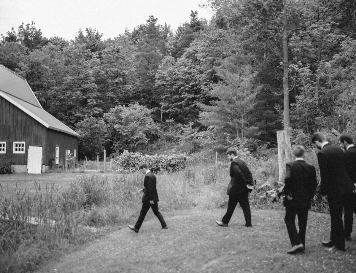 documentary black and white wedding photography, groomsmen walk to venue