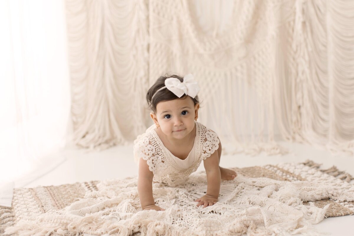 Baby does a crawl on her first birthday session for Medina photographer