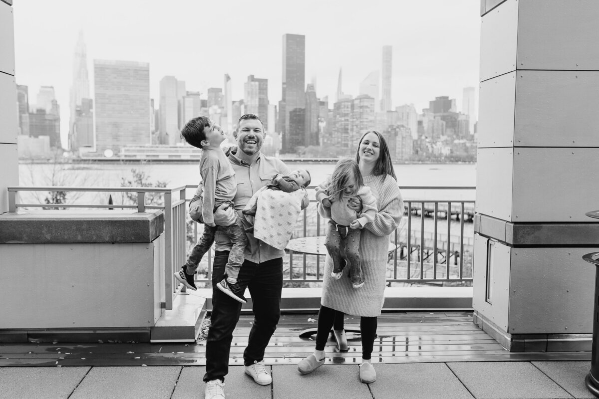 Family Photographer, dad holds young son and mom holds daughter with city scape behind them