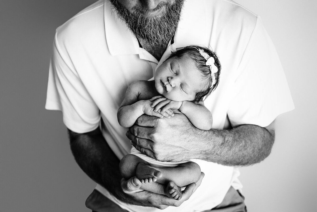 Black and white image of dad holding baby girl in arms  in Jacksonville, FL.