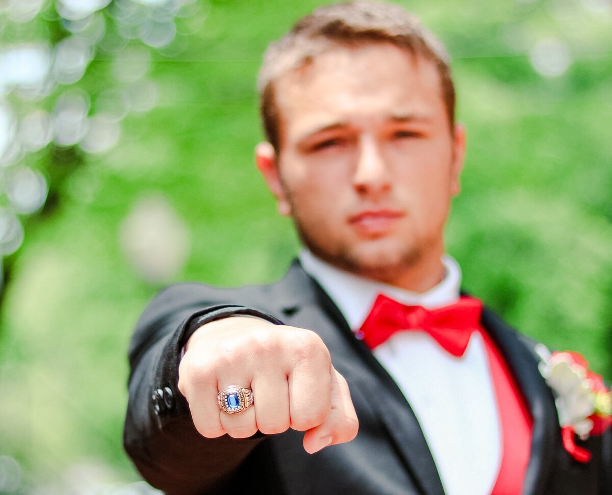 Senior guy in a tux showing off his class ring