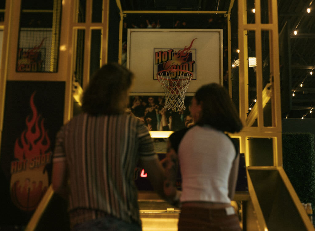 Two people playing a basketball arcade game together.