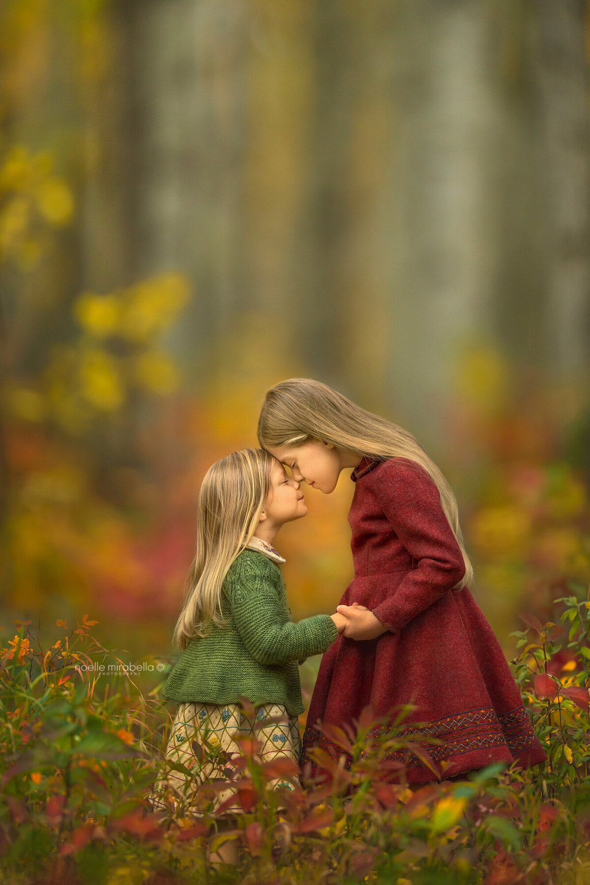 Girls in wool dresses holding hands in autumn.