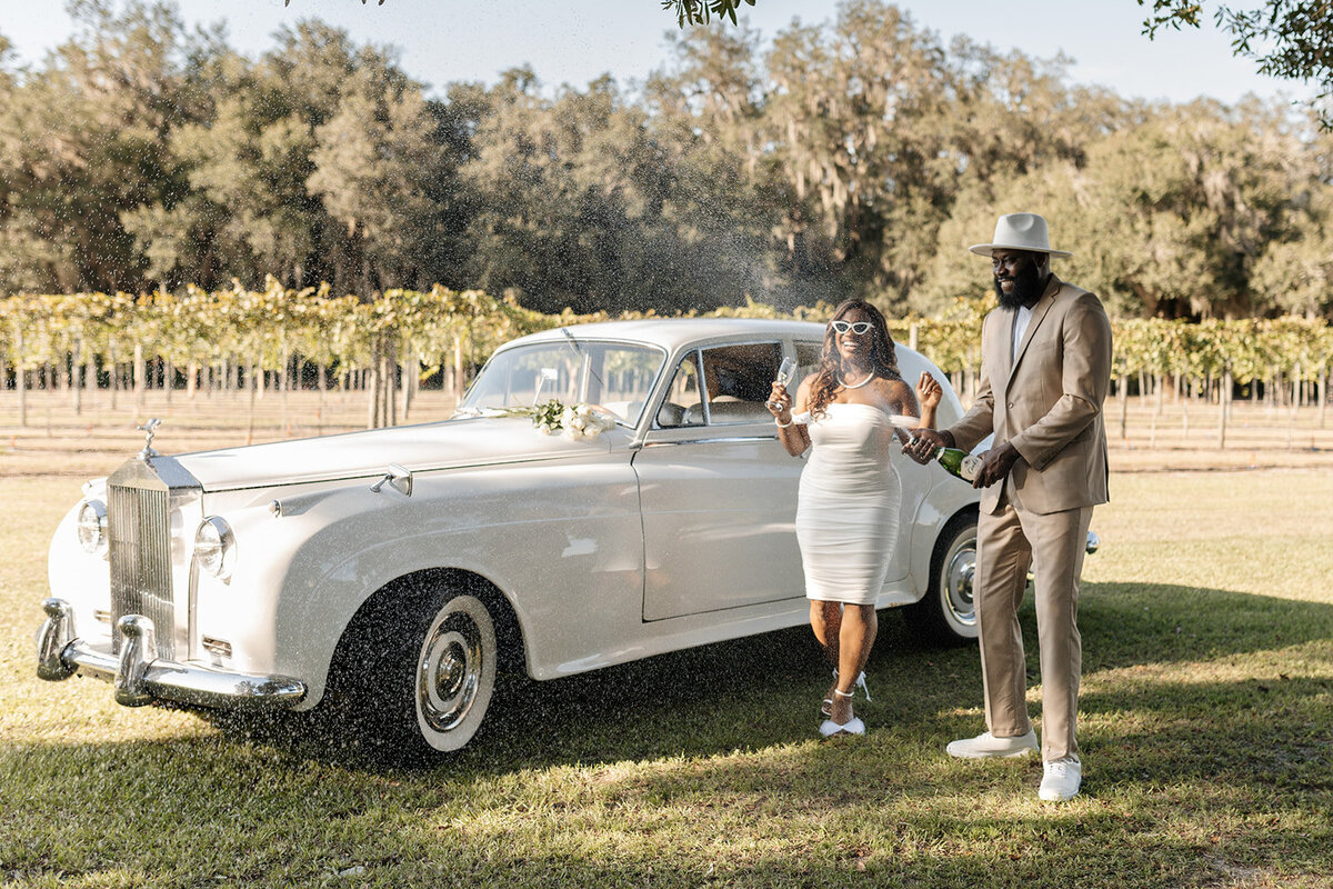 bride and groom next to vintage car on wedding day