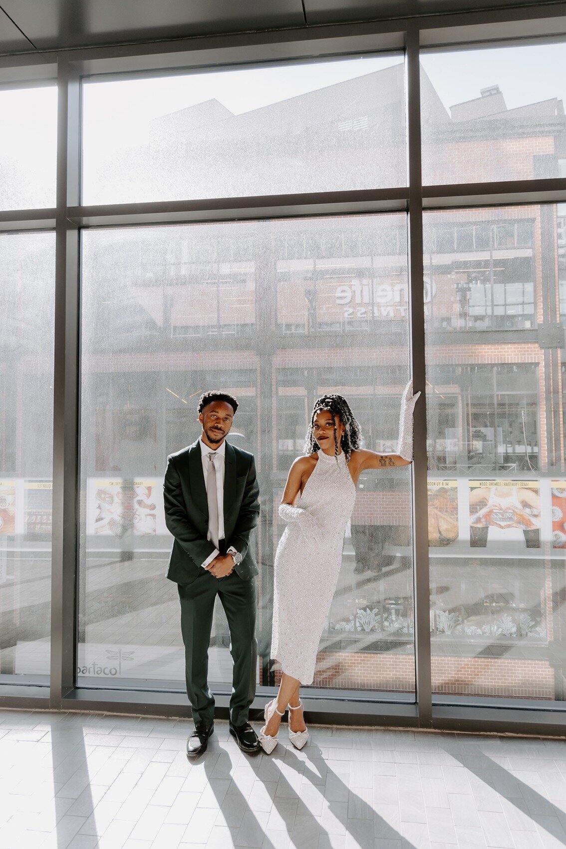 Bride and groom standing on a glass wall with a fierce look
