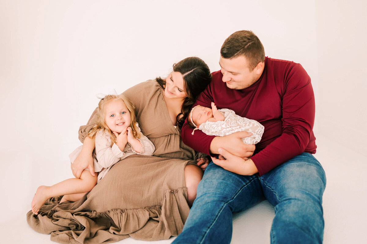 Springfield Mo newborn photogarpher Jessica Kennedy of The Xo Photography captures toddler girl smiling cuddling parents and baby sister