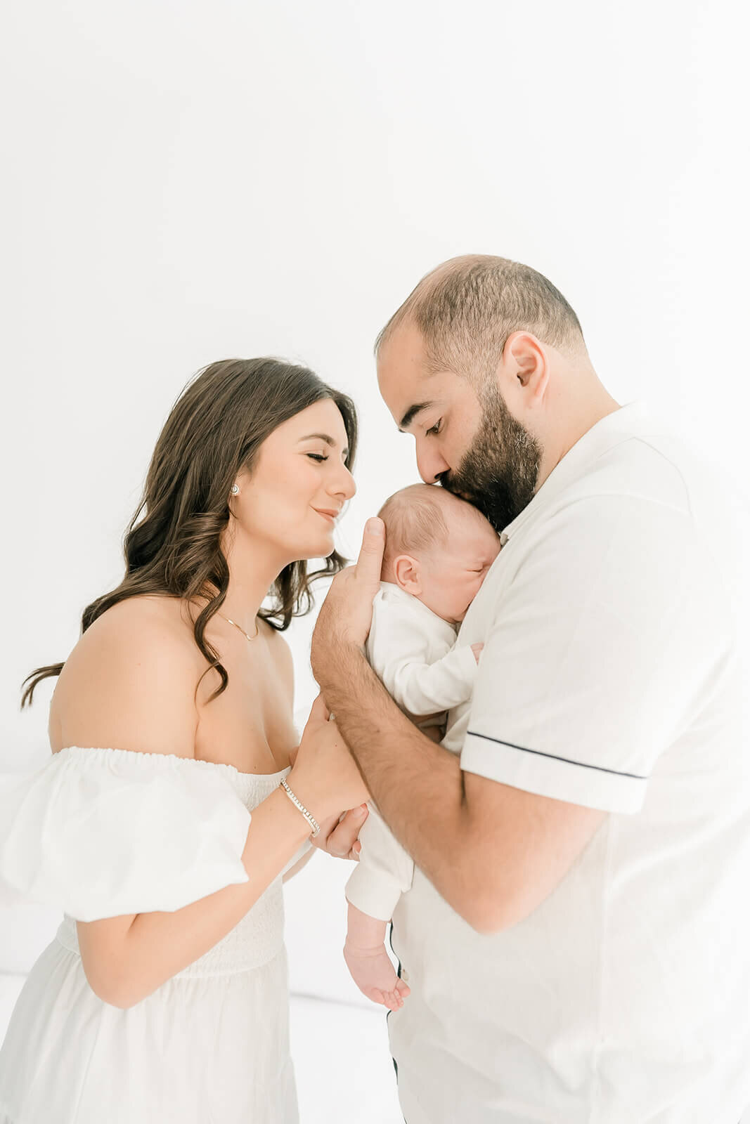 Parents smiling at newborn swaddled in cream blanket during East Bay portrait session.