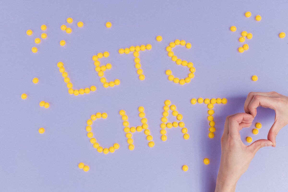 Purple backdrop with lemon heads spelling out "Let's chat" and two hands making a heart.