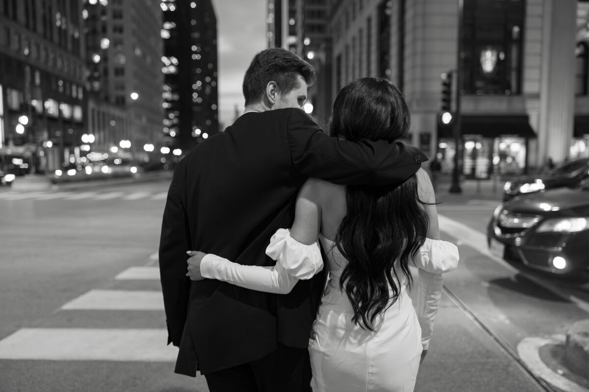 A couple embraces at dusk along Michigan Avenue and the Chicago River, with the city lights creating a romantic and timeless backdrop.