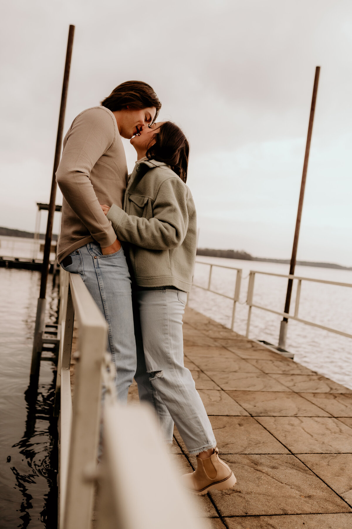 Little rock engagement photographer captured woman leaning against a man as he leans down and kisses her while she wraps her arm around him at the waist