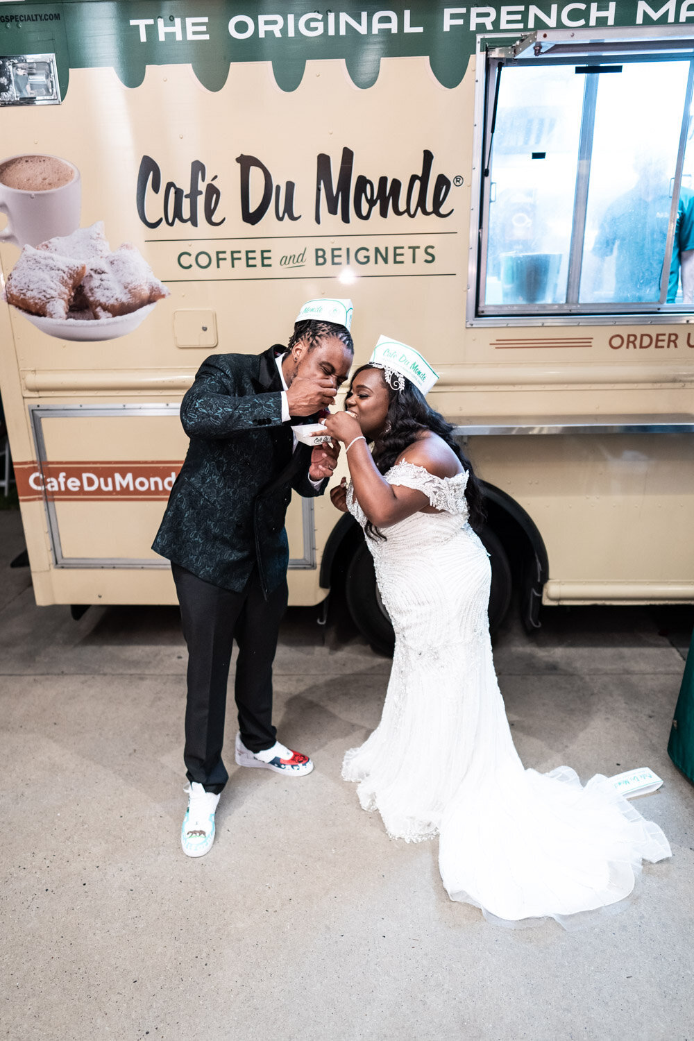 Bride and groom eating beignets in front of Cafe du Monde food truck at Southern Oaks
