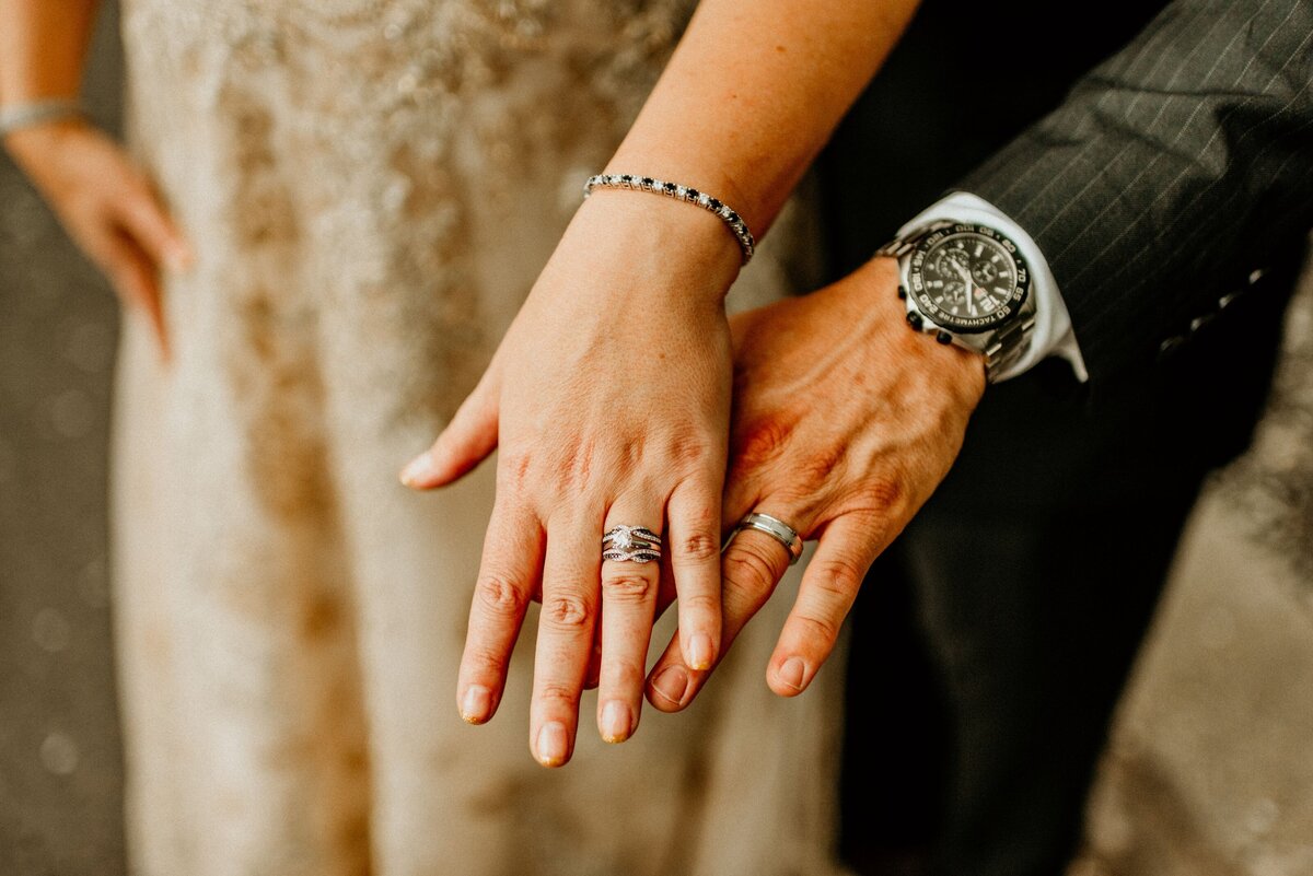 a bride and groom showing off their wedding bands