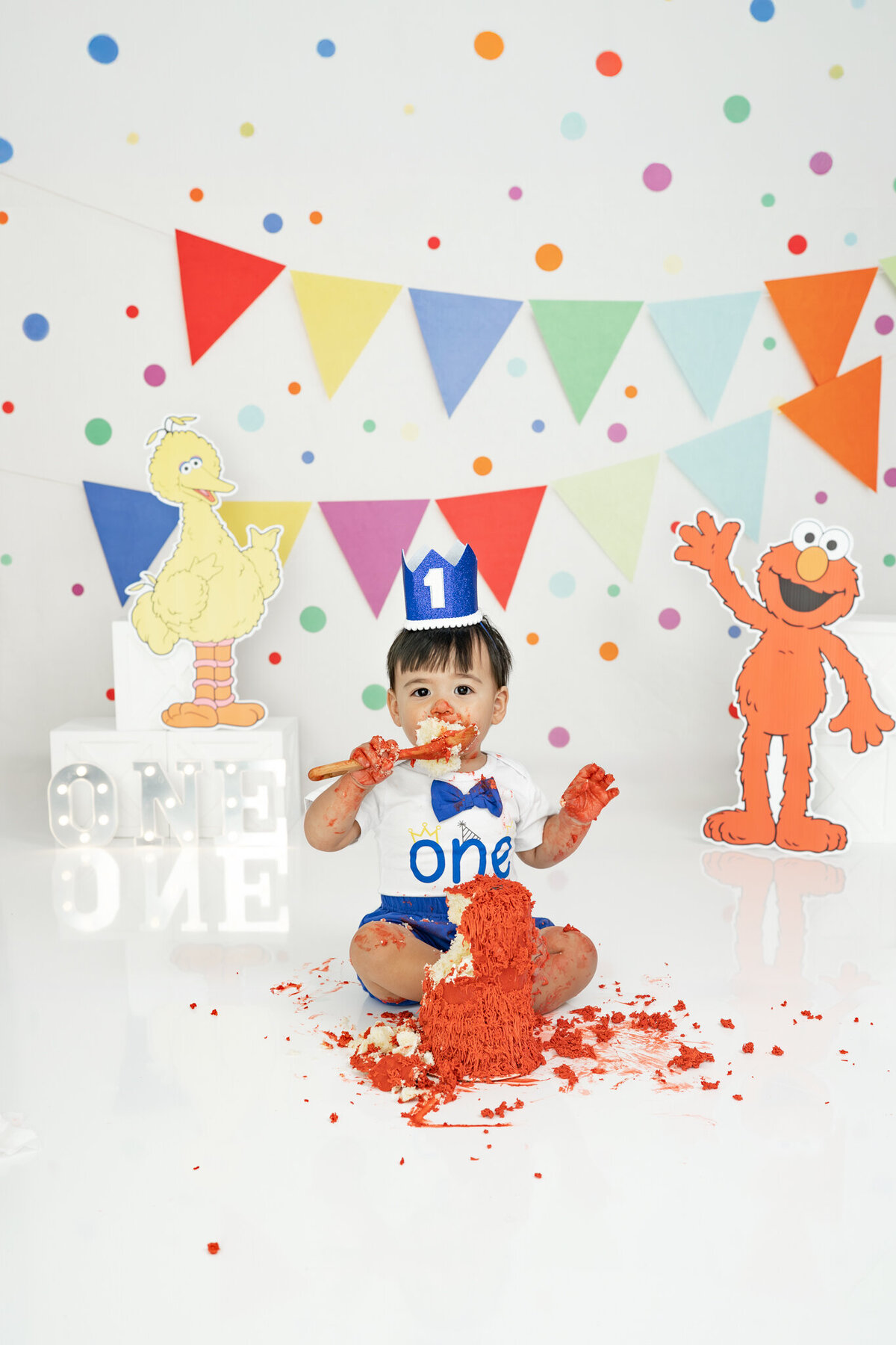 Boy in birthday outfit eating an Elmo cake during themed cake smash session— captured by Alliston and Barrie cake smash photographer.