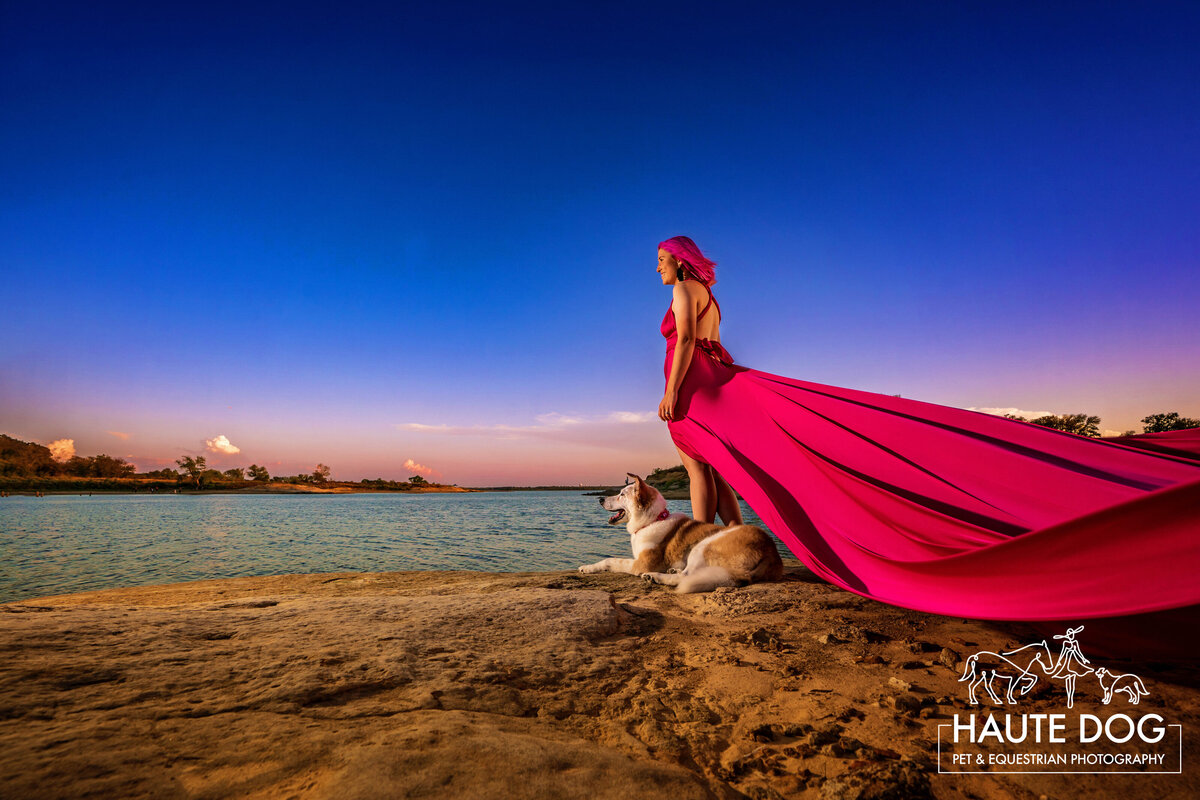 A Collie dog lies on the edge of Grapevine Lake next to a woman wearing a long pink flying dress.