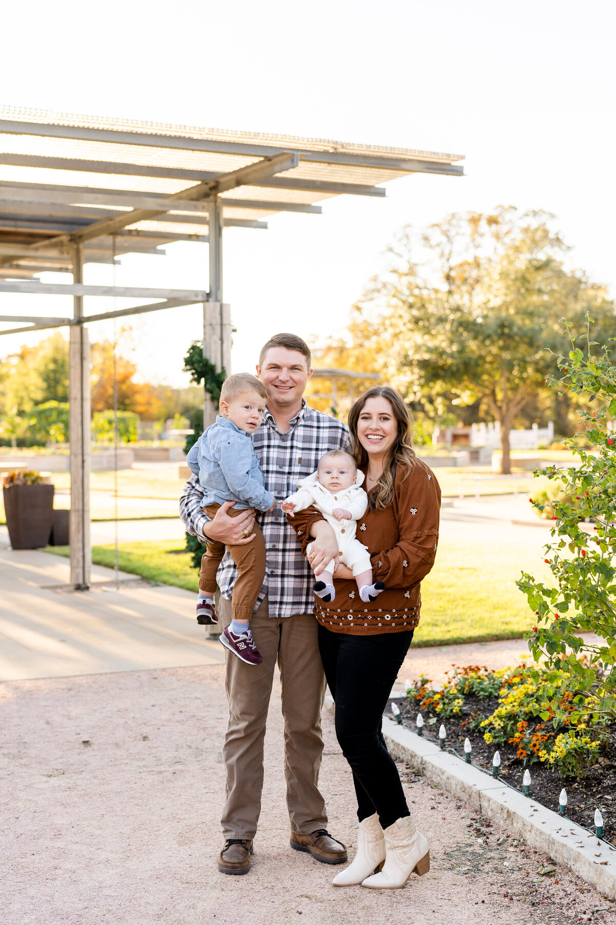 Family with little kids smiling at camera  during golden hour sunset at Leach Teaching Gardens