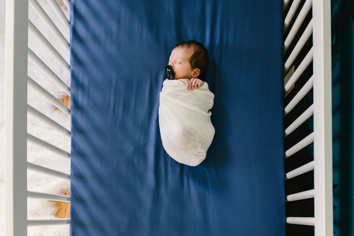 newborn swaddled in crib with a birds eye view