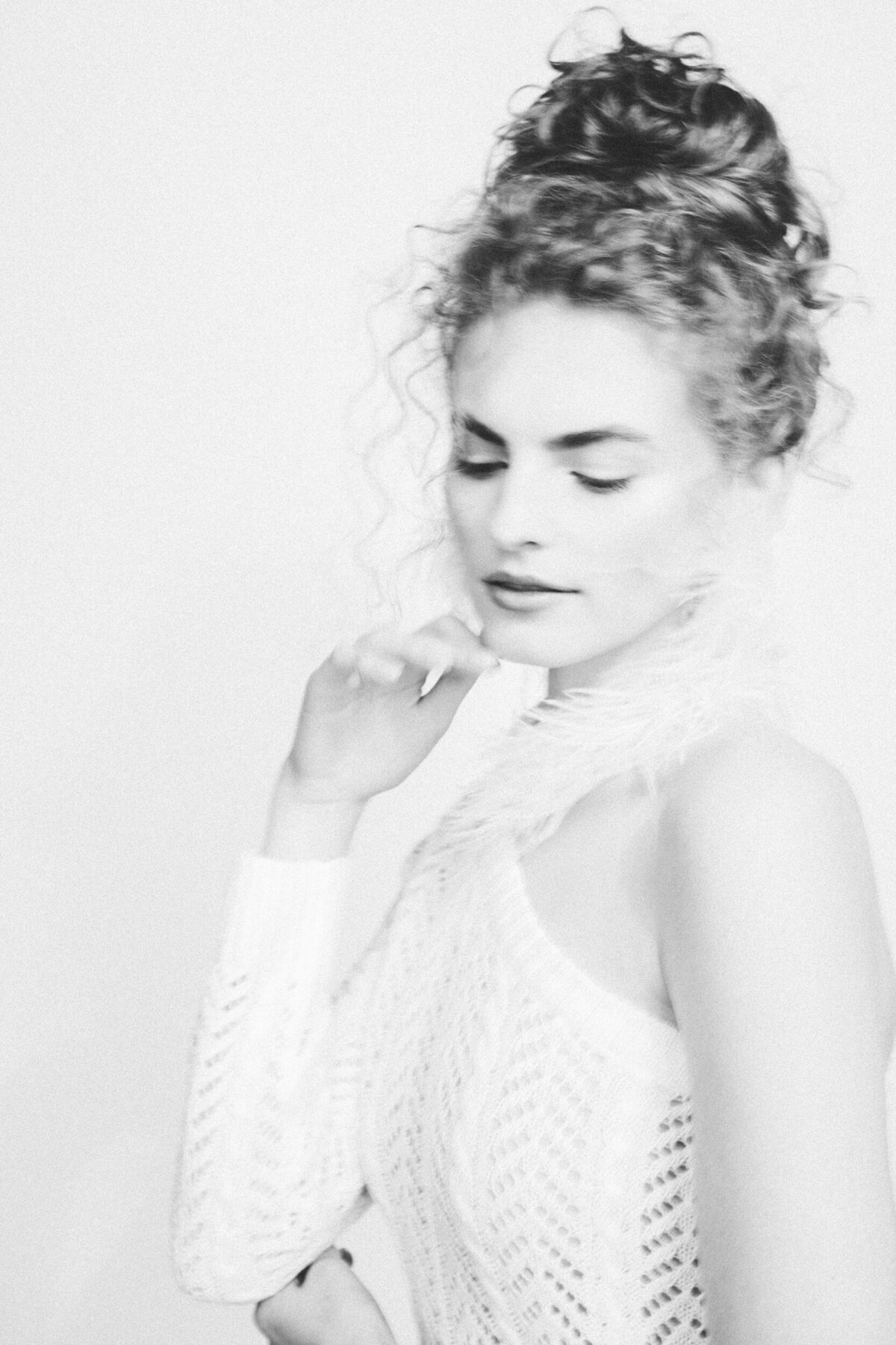 a woman looking down and softly touching her face