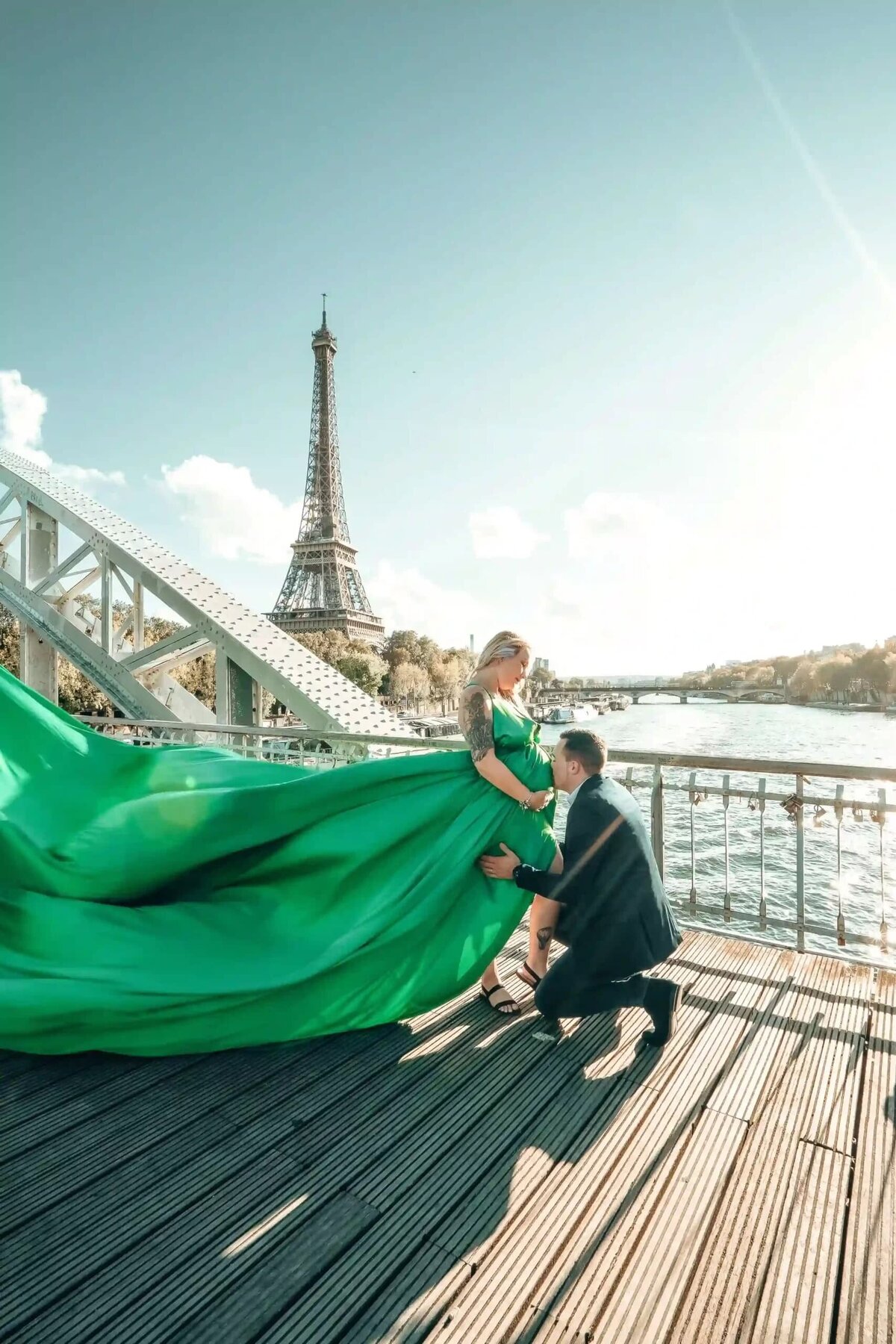 a couple having a photoshoot in front of the eiffel tower with a green flying dress