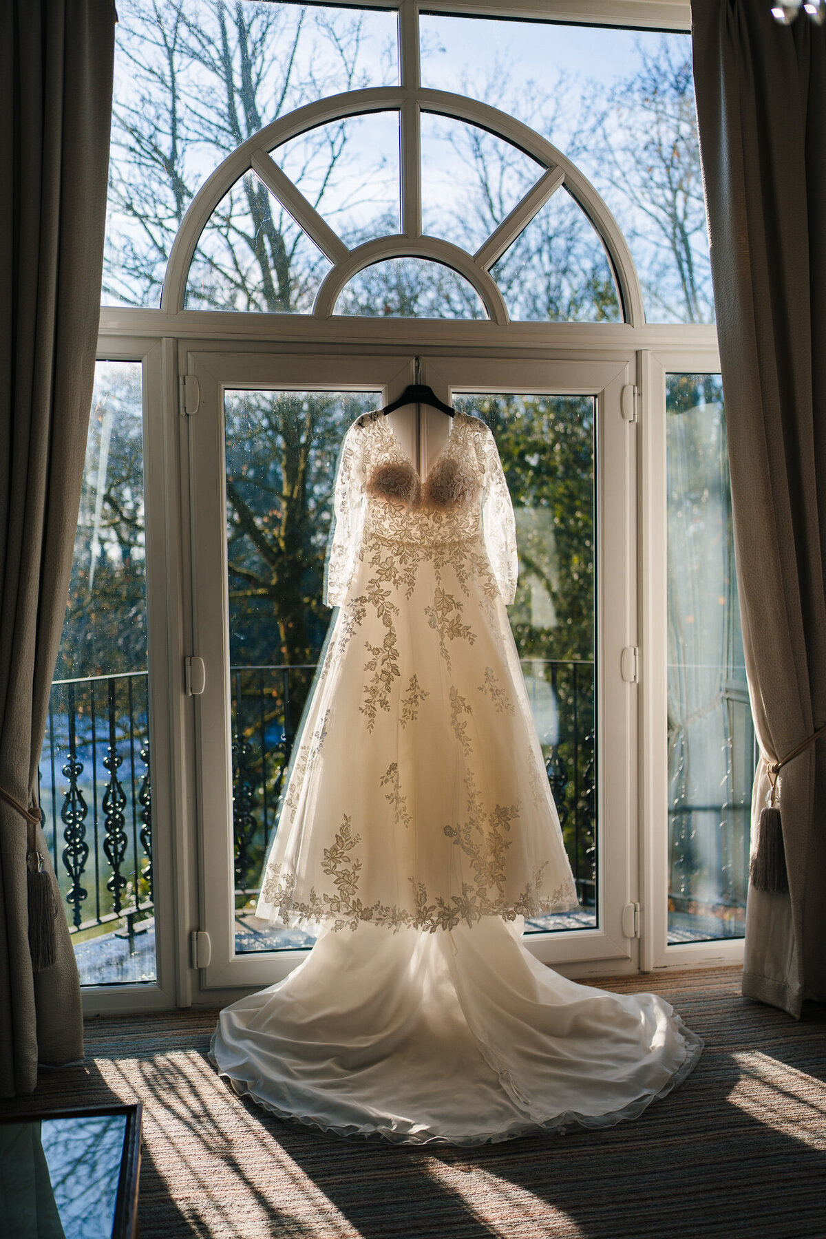 Wedding dress hung up with the sun shining through takne at Ashfield House by Wwedding Photographer Anthony Horseman