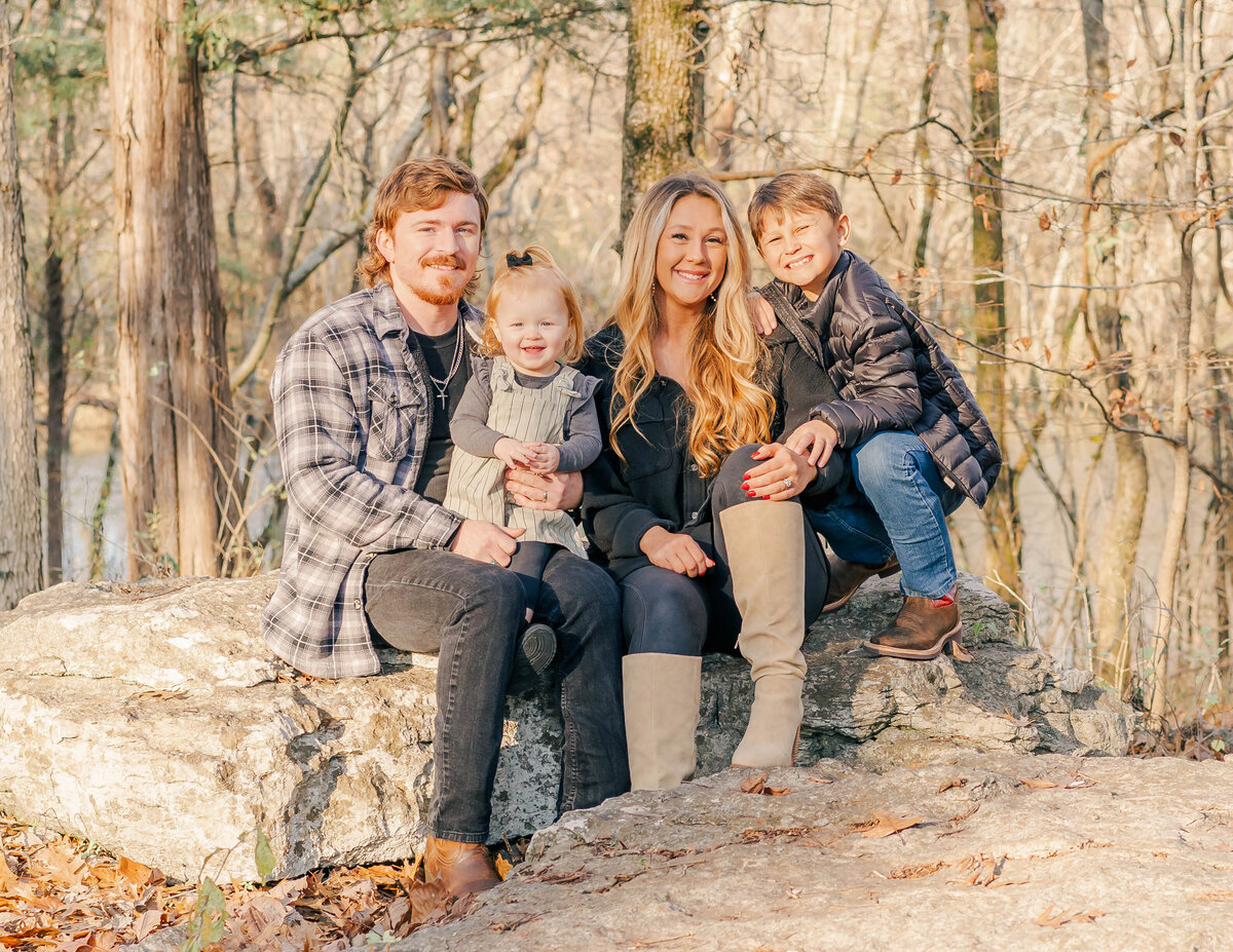 family posing on rocks at river during their fall photo session at Old Fort Park