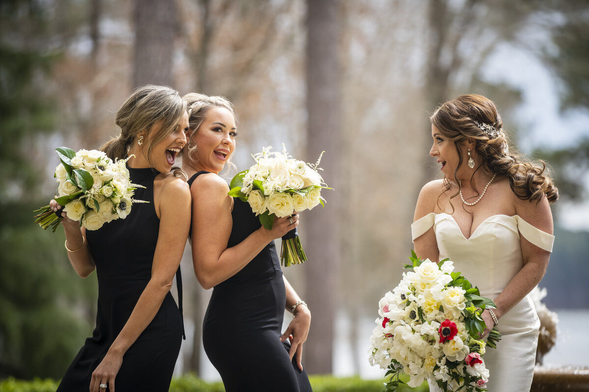 Bridesmaids in black dresses making bride laugh.