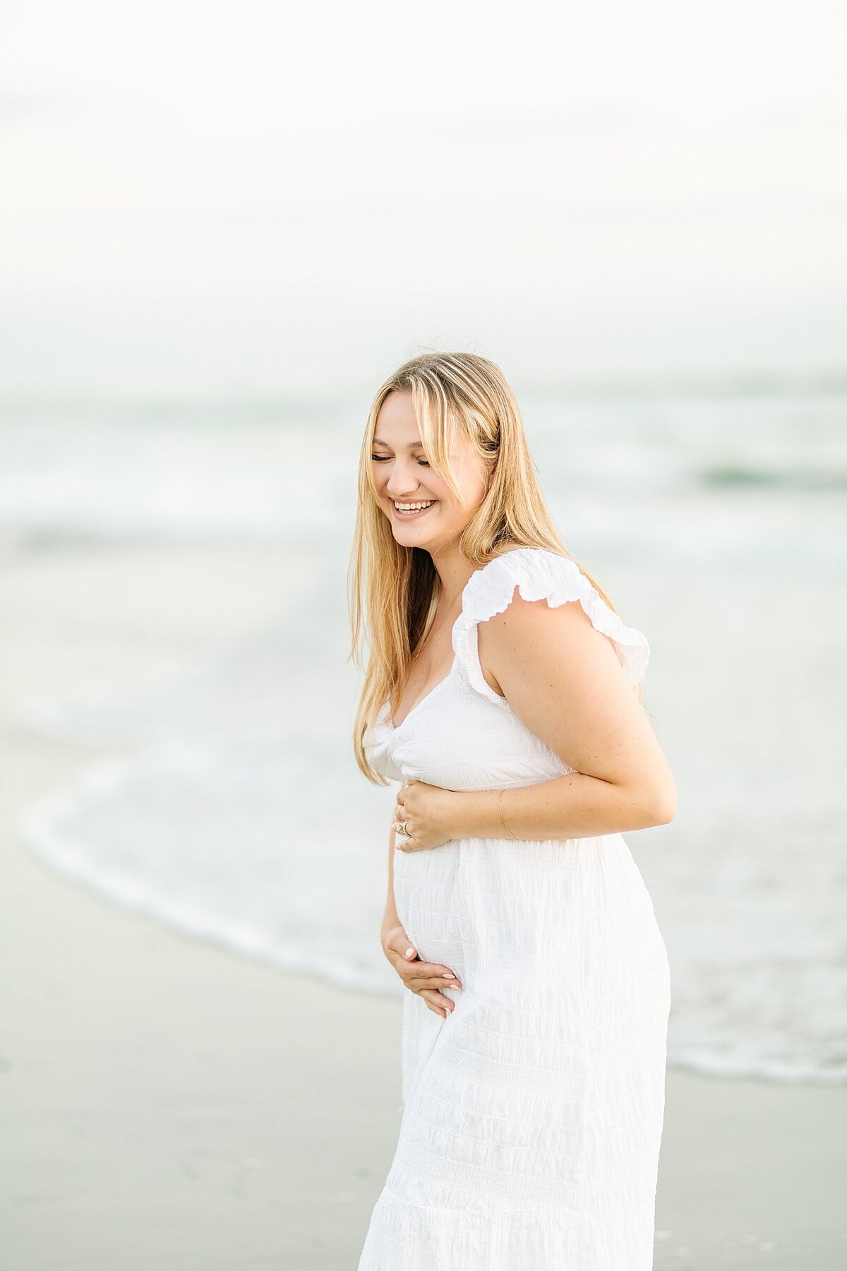 Pregnant mama holding baby bump at the beach in Del Mar by photographer, Bree Sherr.