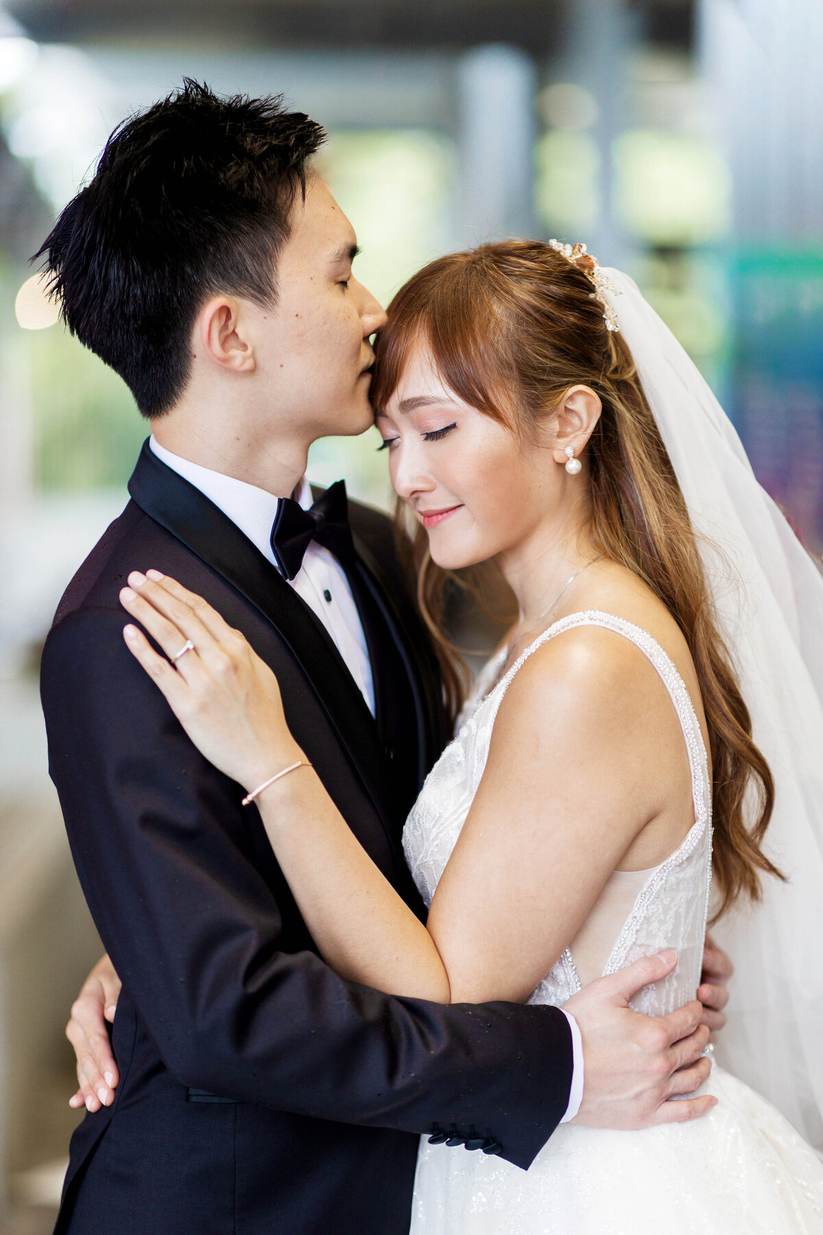 Groom kissing bride’s forehead during an intimate wedding portrait at the Great Court, UQ St Lucia — Brisbane wedding photography.